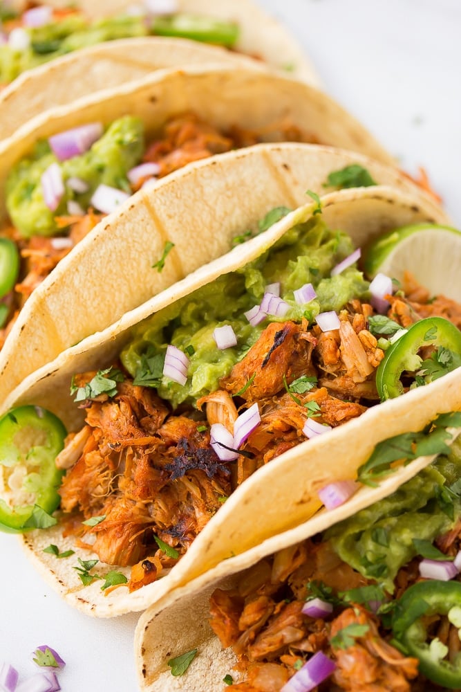 jackfruit carnitas in corn tortillas with lettuce, onion and guacamole