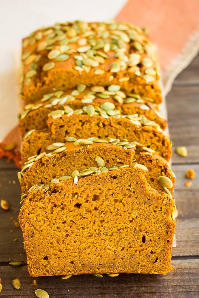 sliced pumpkin loaf with brown wood background and orange towel