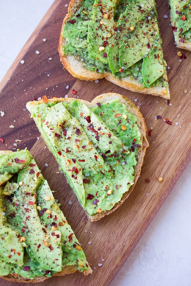 close up of a half of avocado toast sprinkled with red pepper and salt