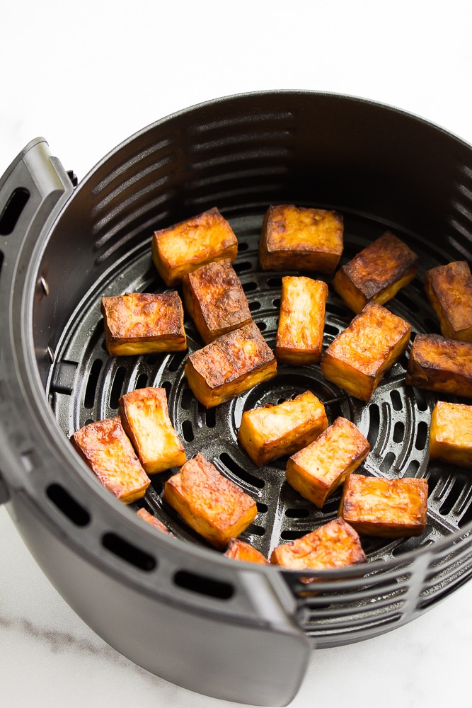the inside of an air fryer with tofu on it, cooked and crispy