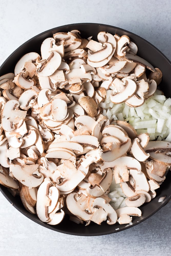 uncooked mushrooms and onions in a pan