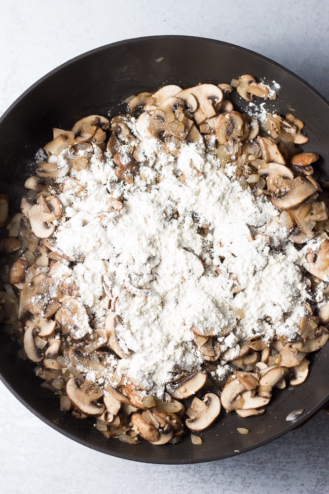 mushrooms cooked in a pan, flour sprinkled on top.