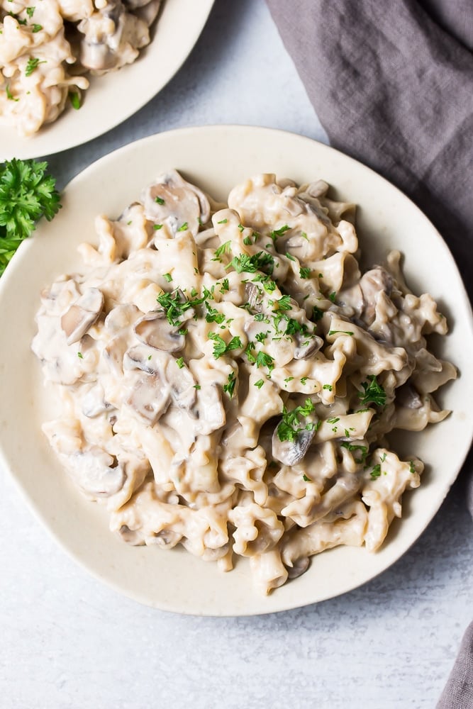 looking down on a plate of vegan mushroom stroganoff, gray towel in background.