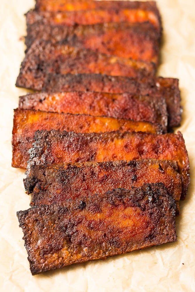 tofu bacon stacked in a row on parchment paper