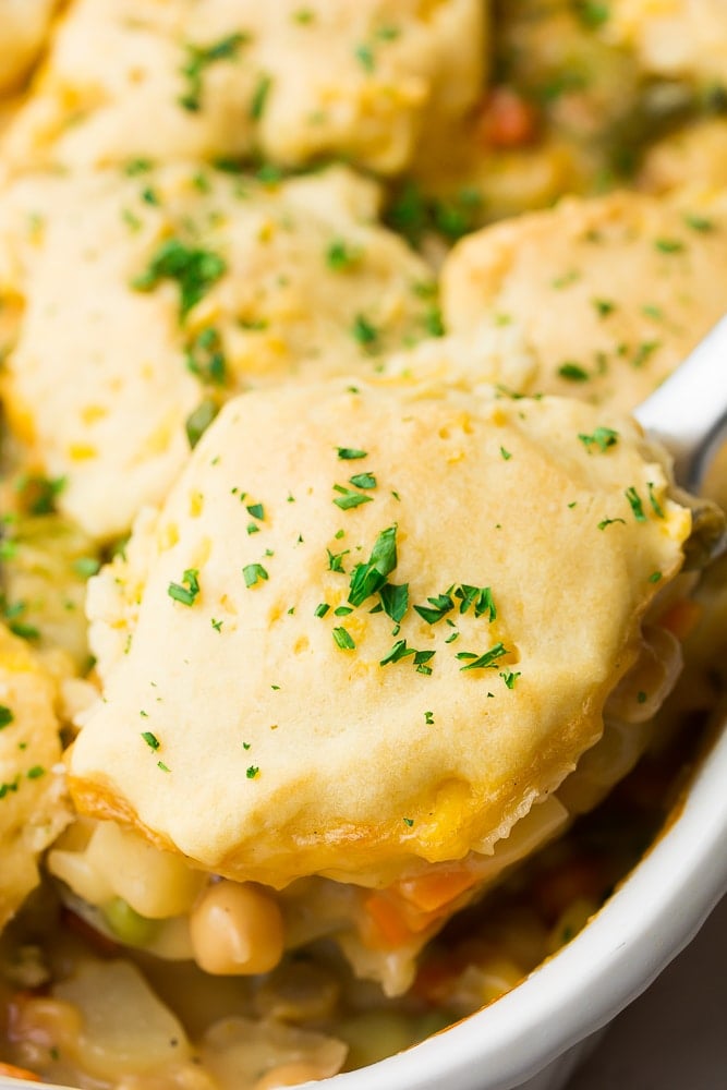 silver spoon serving out a biscuit topped pot pie from casserole dish