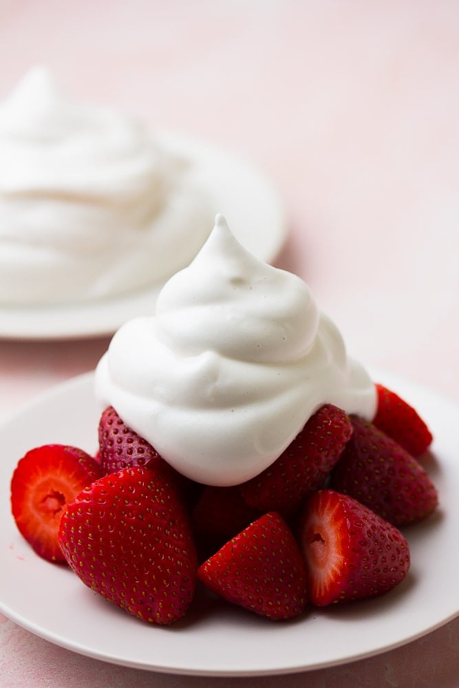 whipped cream on strawberries with pink background