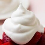 very close up shot of vegan whipped cream on a plate of strawberries with pink background