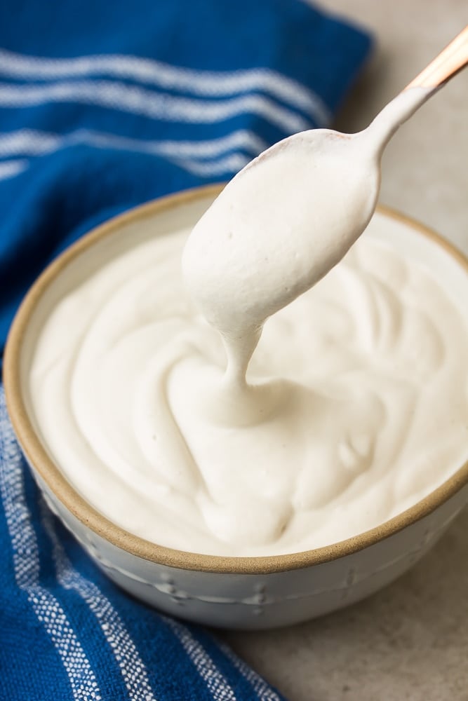 spoon lifting out some cashew cream on it from a bowl