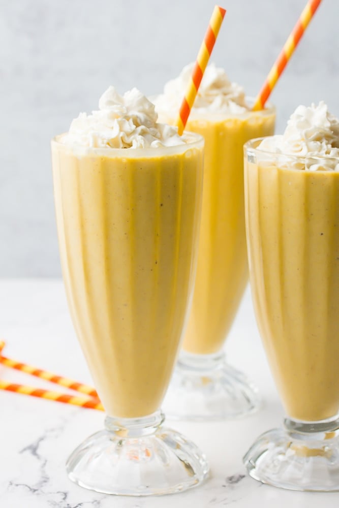 side shot of milkshakes with orange straws and whipped cream