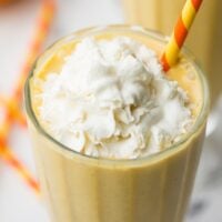 close up of top of pumpkin milkshake with whipped cream and colorful straw
