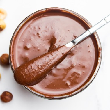 vegan nutella on a knife, sitting on a glass bowl.