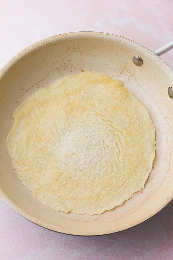 crepe in a pan flipped over cooking on second side