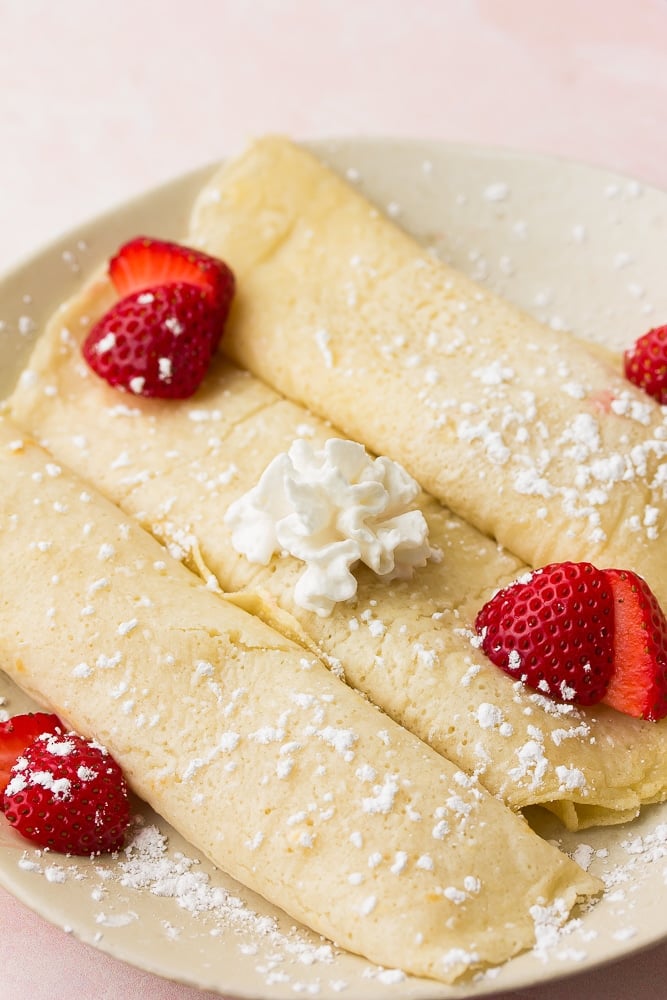 3 rolled crepes with strawberries, whipped cream and powdered sugar