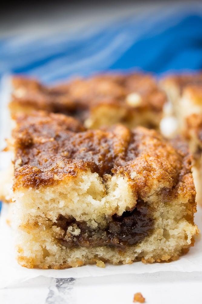 piece of vegan coffee cake with blue towel in back and more cake