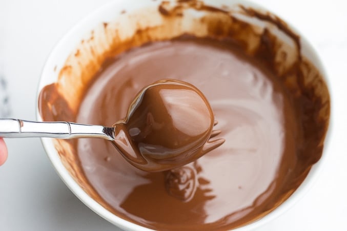 peanut butter ball being dipped in melted chocolate