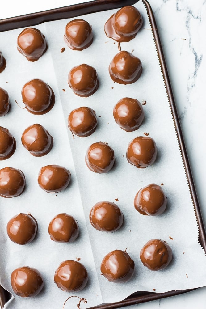 dipped in chocolate peanut butter balls on parchment lined pan