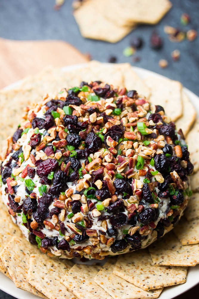whole cranberry pecan coated vegan cheese ball with crackers around it