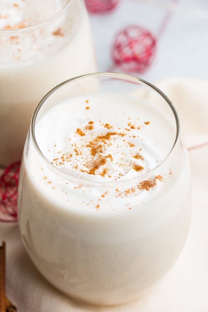 glass of vegan eggnog with spices sprinkled and red towel