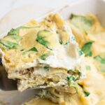 piece of white lasagna being taken out of casserole dish