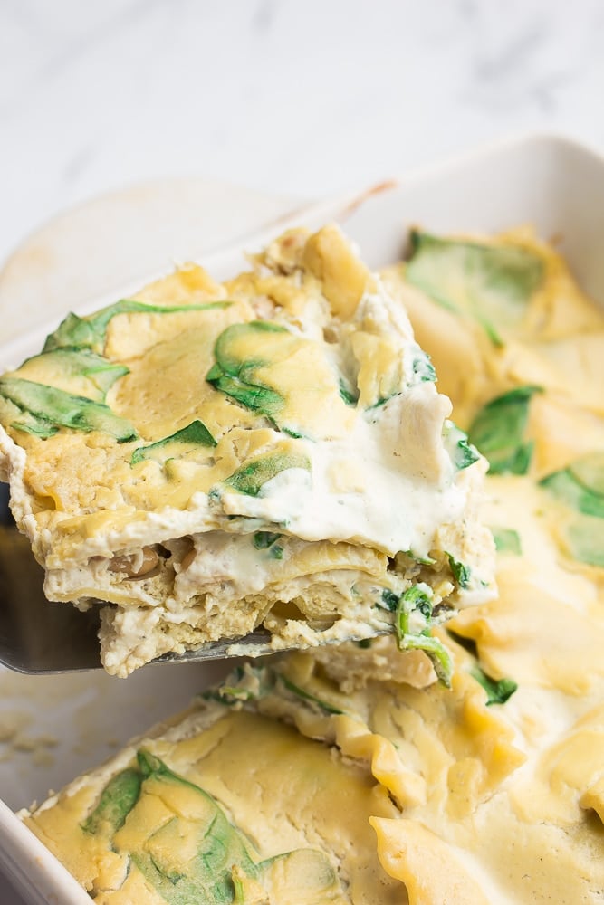 piece of white lasagna being taken out of casserole dish