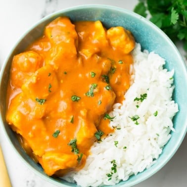 looking down on a bowl of tikka masala in turquoise bowl with white rice