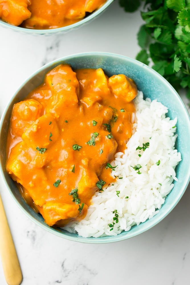 looking down on a bowl of tikka masala in turquoise bowl with white rice