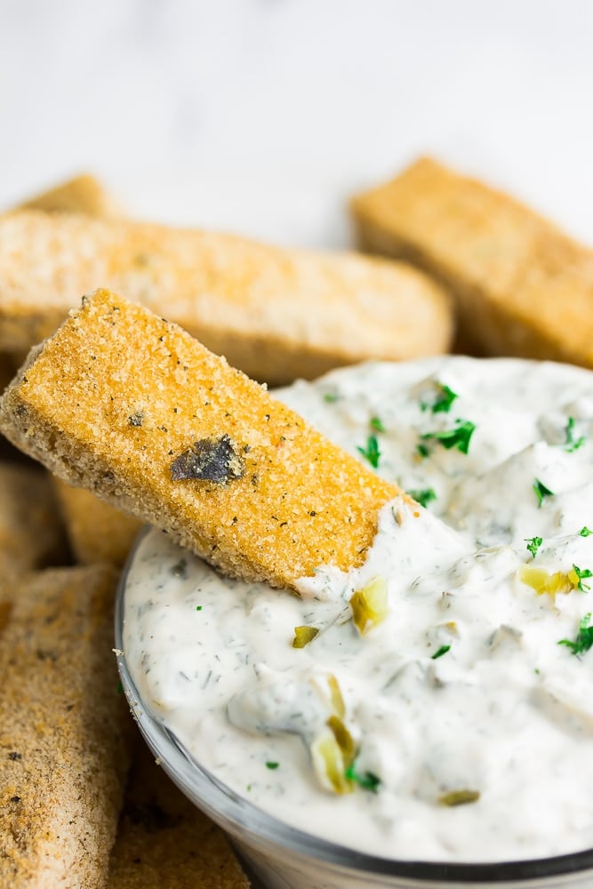 tofu fish being dipped into tartar sauce