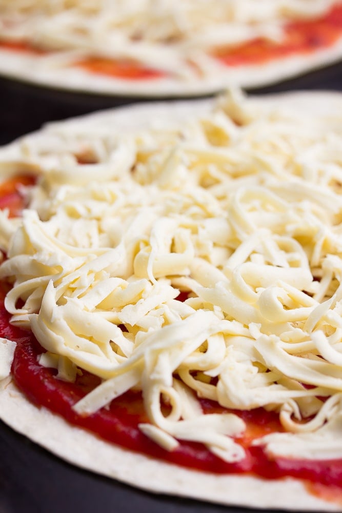 pizza with sauce and shredded cheese on it, not cooked