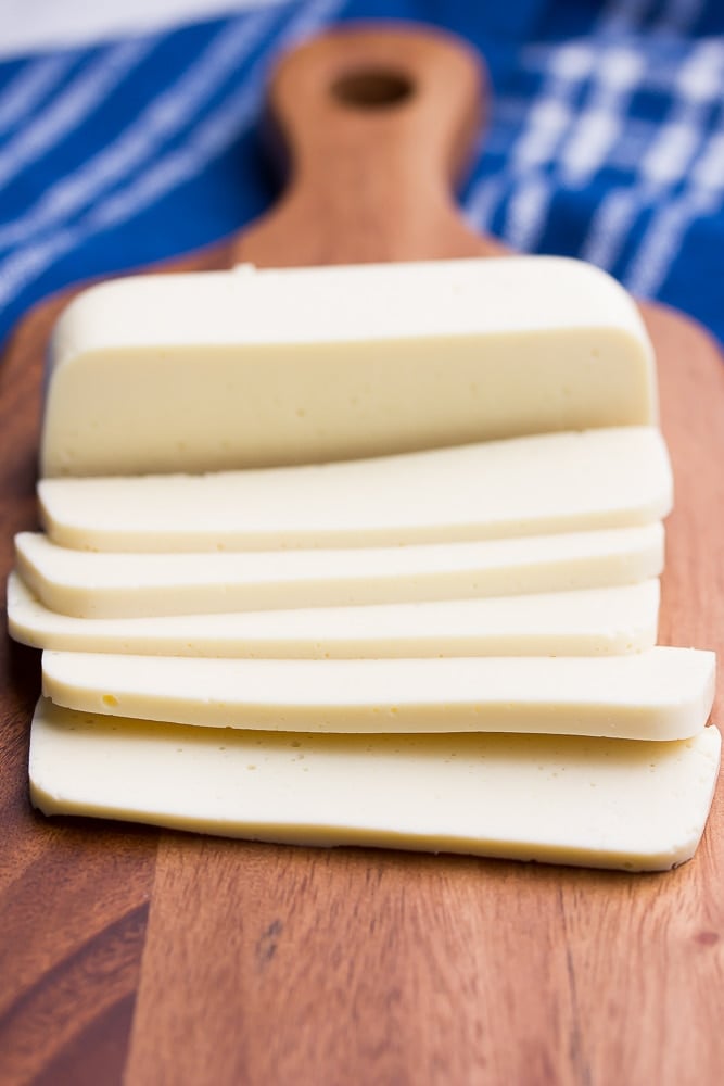 sliced vegan mozzarella cheese with blue towel on a cutting board