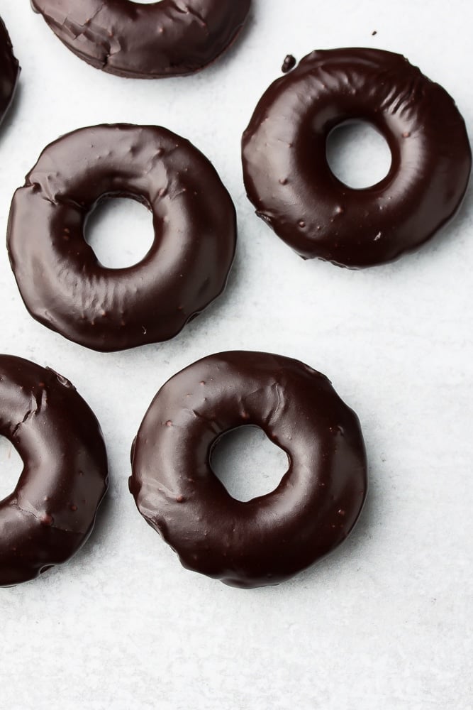 looking down on several chocolate donuts on grey background