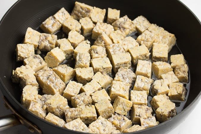 tempeh being cooked in water in a pan