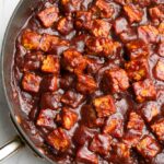 tempeh cubes with bbq sauce in a pan, coated in it.
