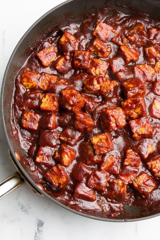 tempeh cubes with bbq sauce in a pan, coated in it.