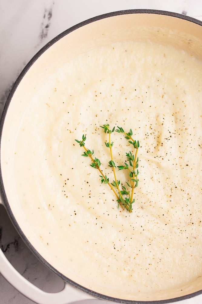 large pot of vegan cauliflower soup, spring of thyme on top.