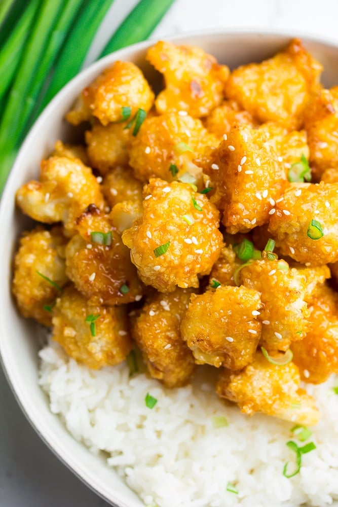 bowl with white rice and orange cauliflower, green onions on top