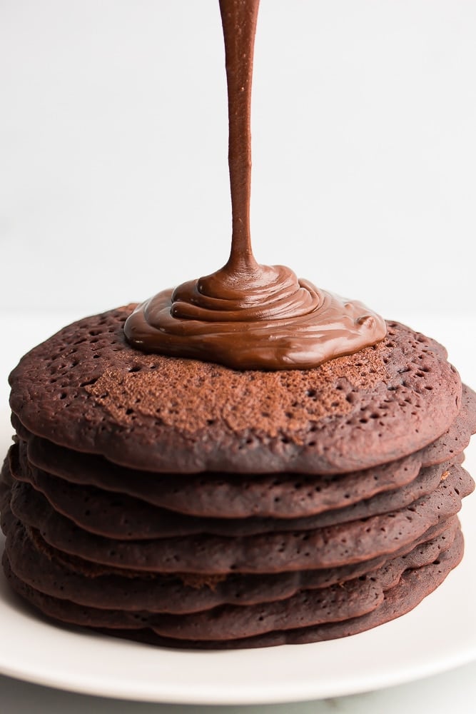 vegan ganache being poured onto chocolate pancakes, white background