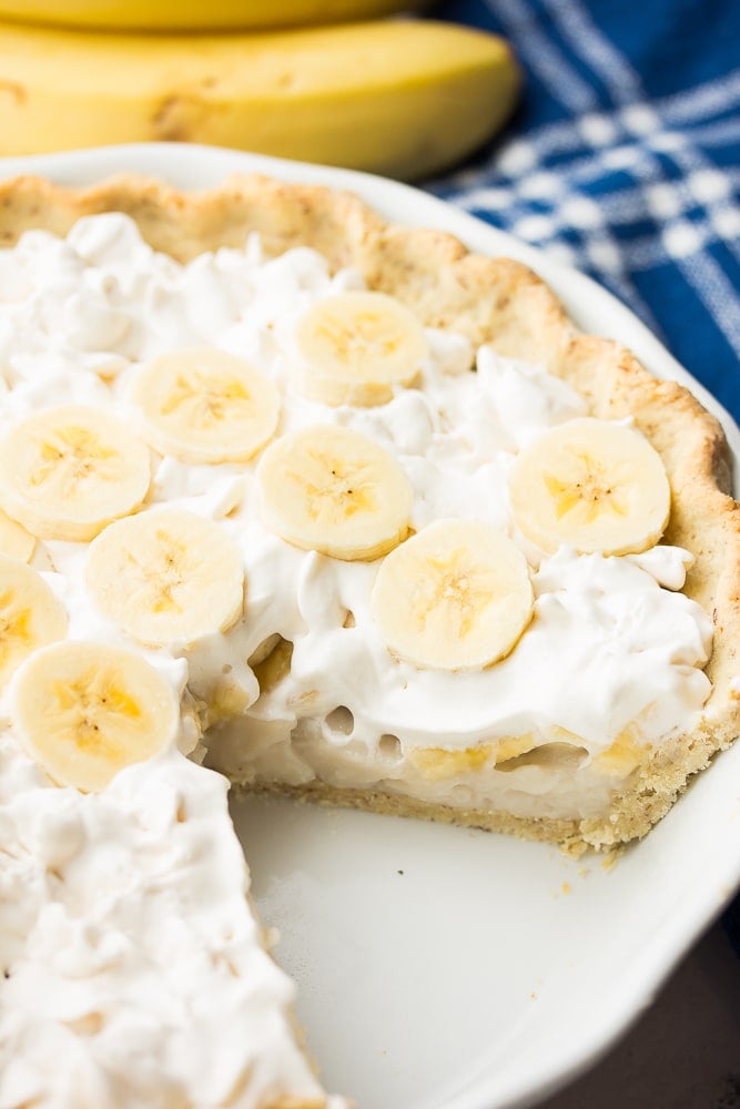 piece of banana cream pie cut out, bananas in back