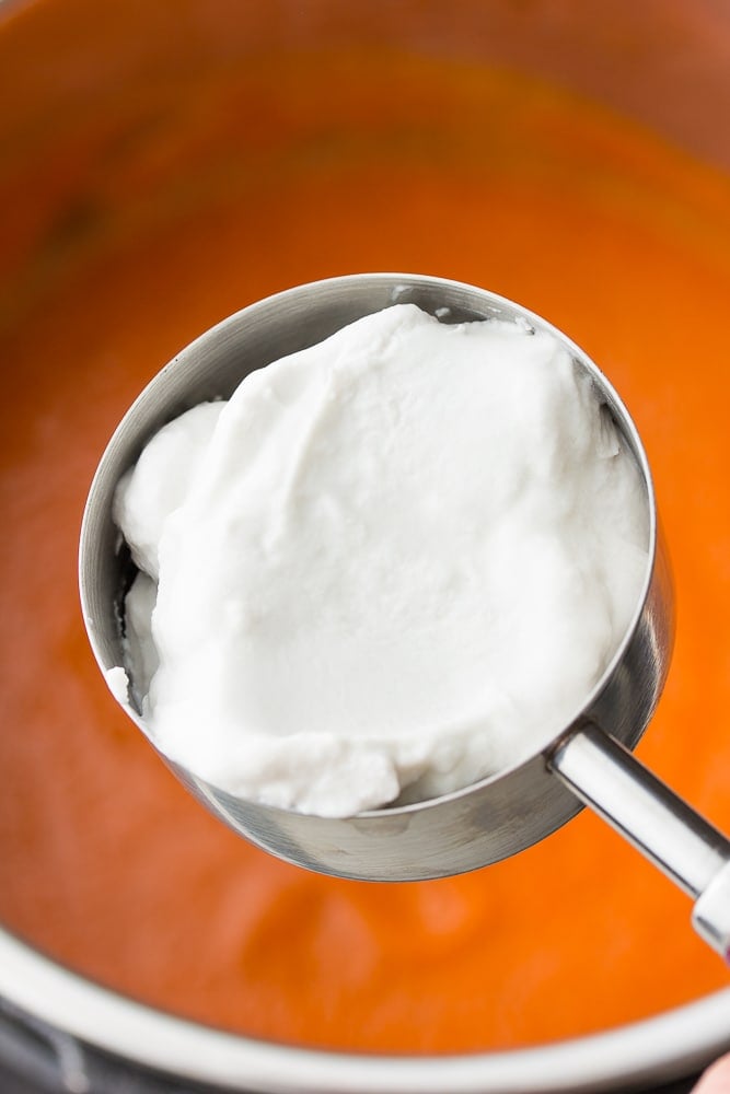 measuring cup with coconut cream being added to soup