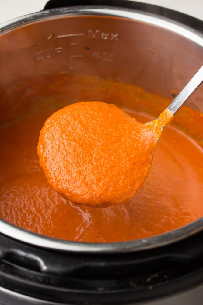 ladle holding tomato soup out of instant pot