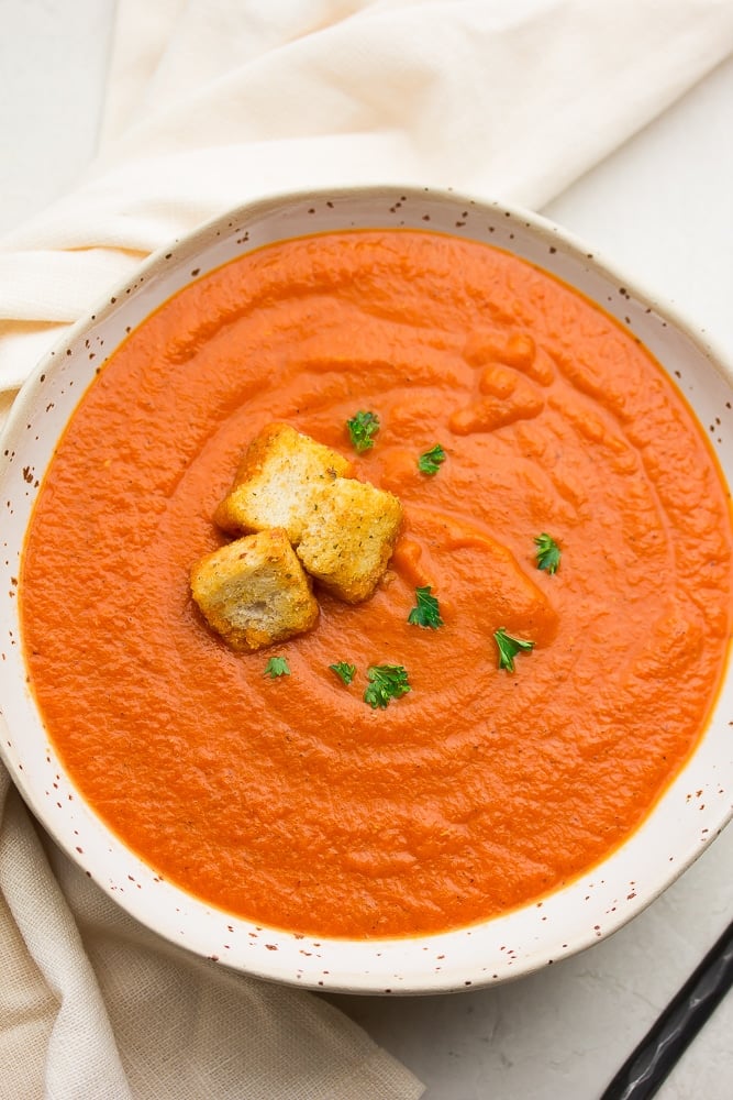 bowl of red/orange soup with croutons