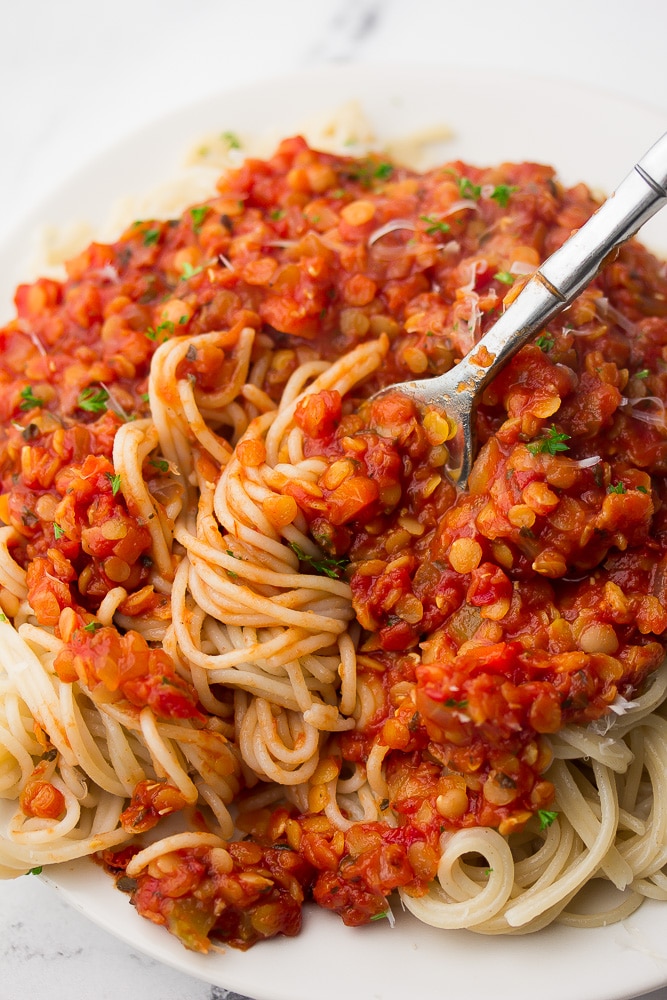 a fork swirling sauce and spaghetti around it on a plate 