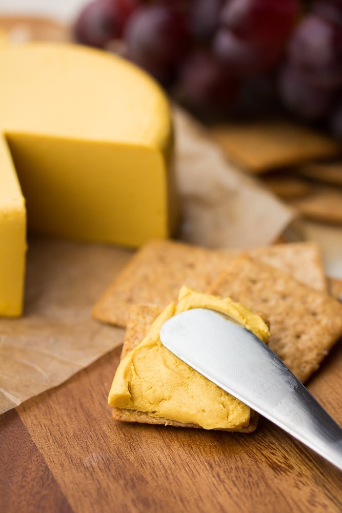 spreading vegan cheddar on a cracker