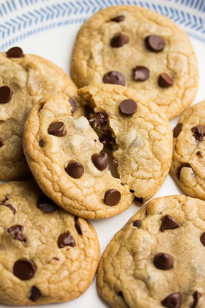a pile of chocolate chip cookies with the top one split in half