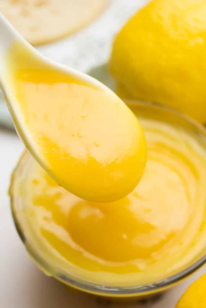 lemon curd dropping from a spoon into a glass container