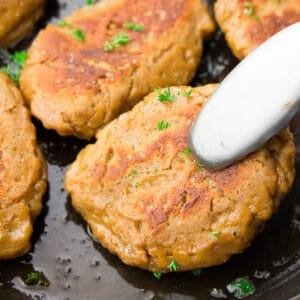 piece of vegan chicken being picked up by tongs from pan