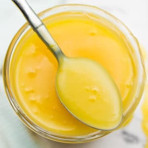 square image of lemon curd on a spoon from a jar