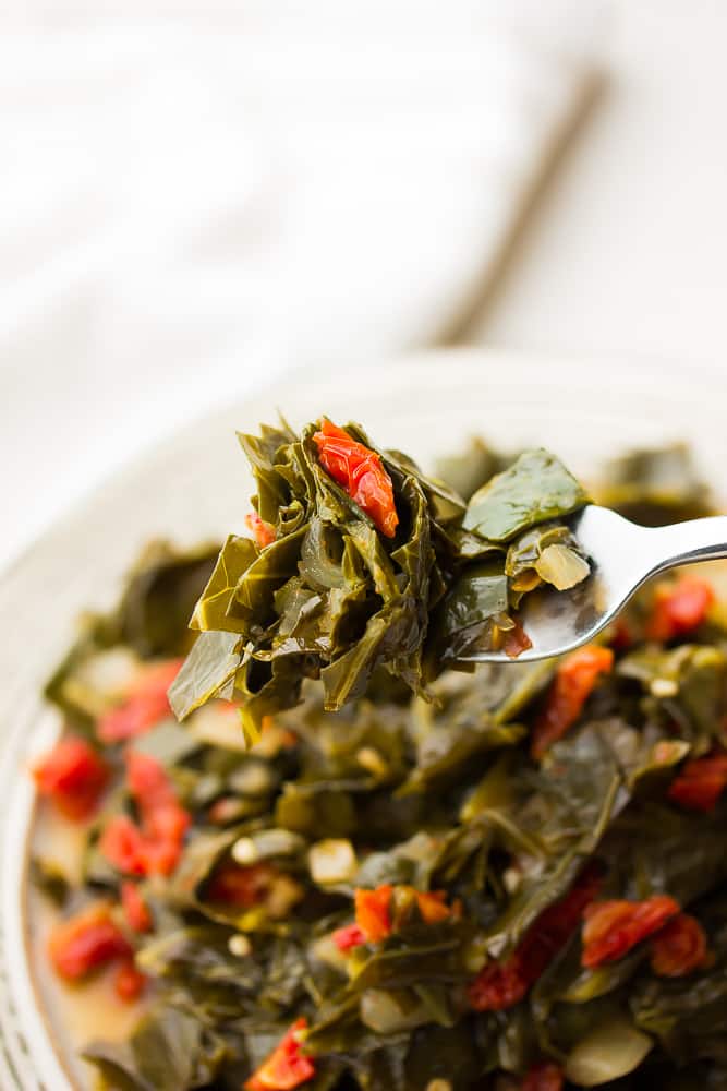 fork holding cooked greens and tomatoes