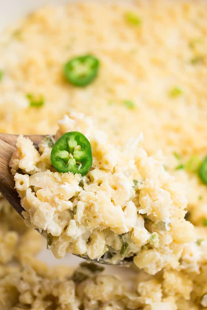 spoonful of mac and cheese with a jalapeño slice from casserole dish