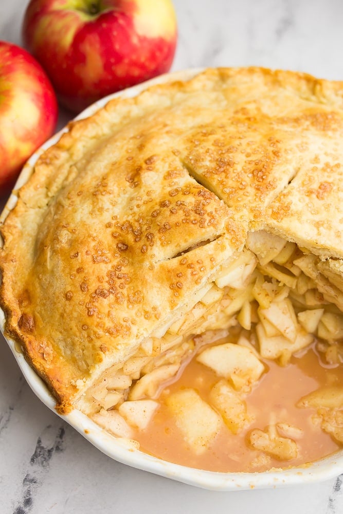 apple pie in pan with slices taken out showing apple mixture inside