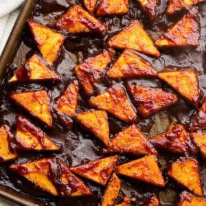 square image of tofu pieces with bbq sauce on them in a pan